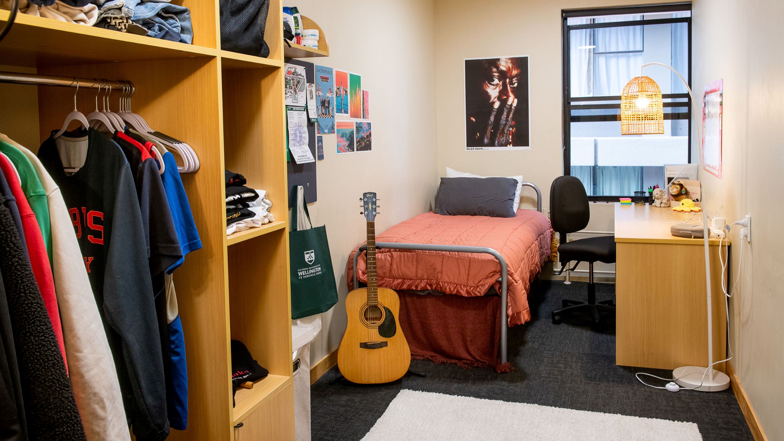 Single room at Joan Stevens Hall, with a bed, wardrobe unit, desk and chair.