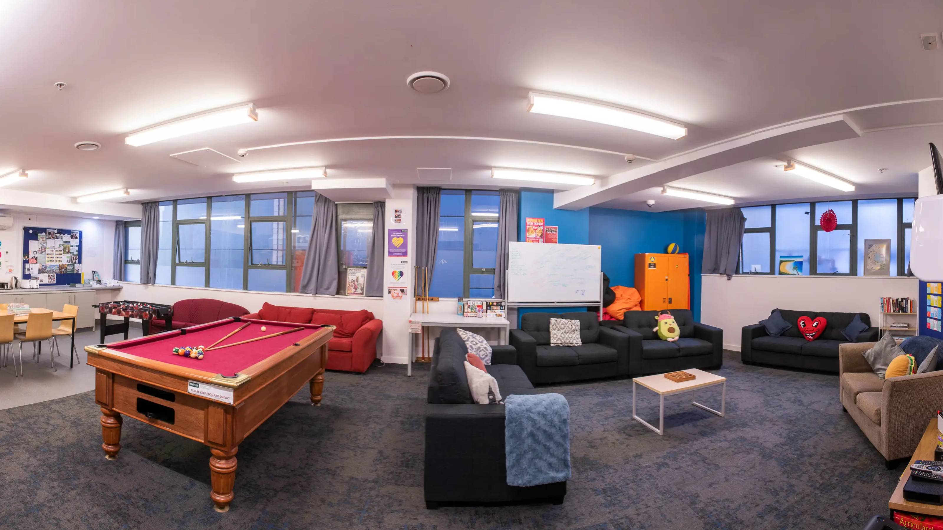 Large common area with kitchen and pool table at Education House
