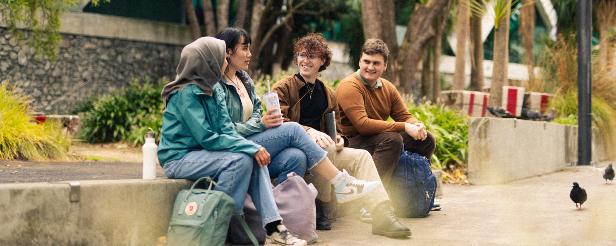Four architecture students sitting in central Wellington, with pigeons in the foreground.