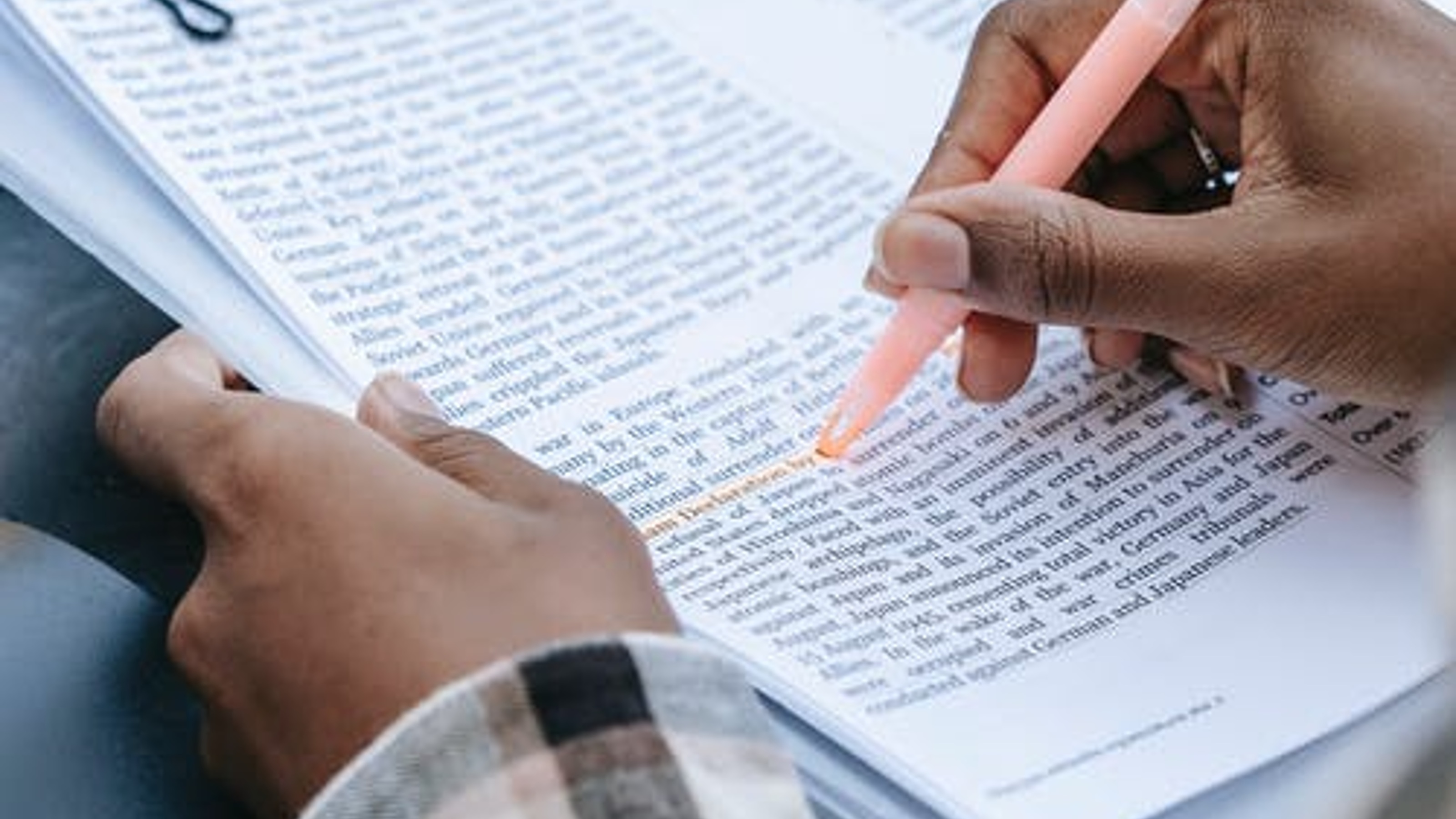 A hand is seen highlighting a textbook