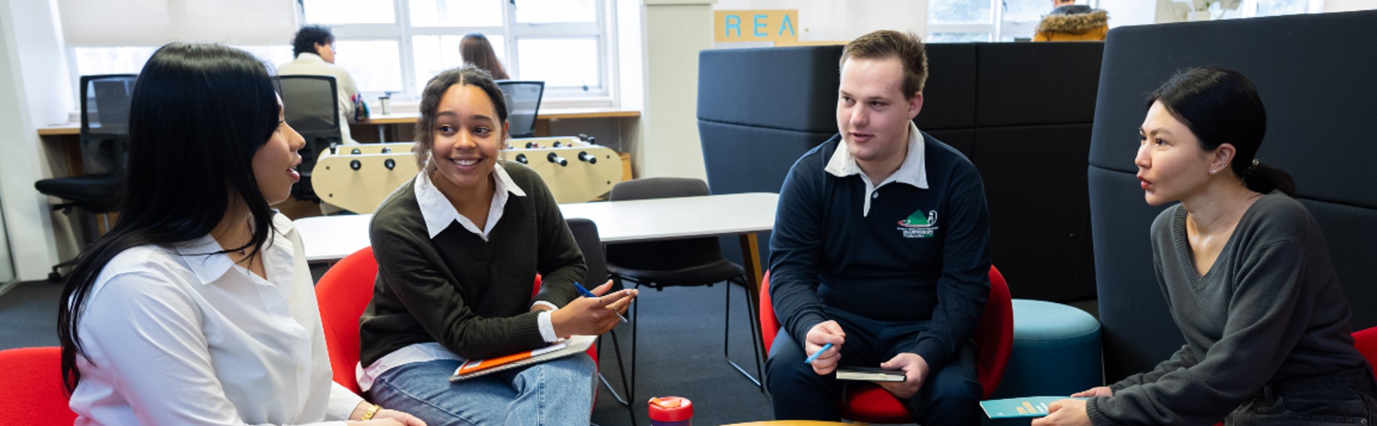 A group of graduates meeting around a laptop in a shared workspace