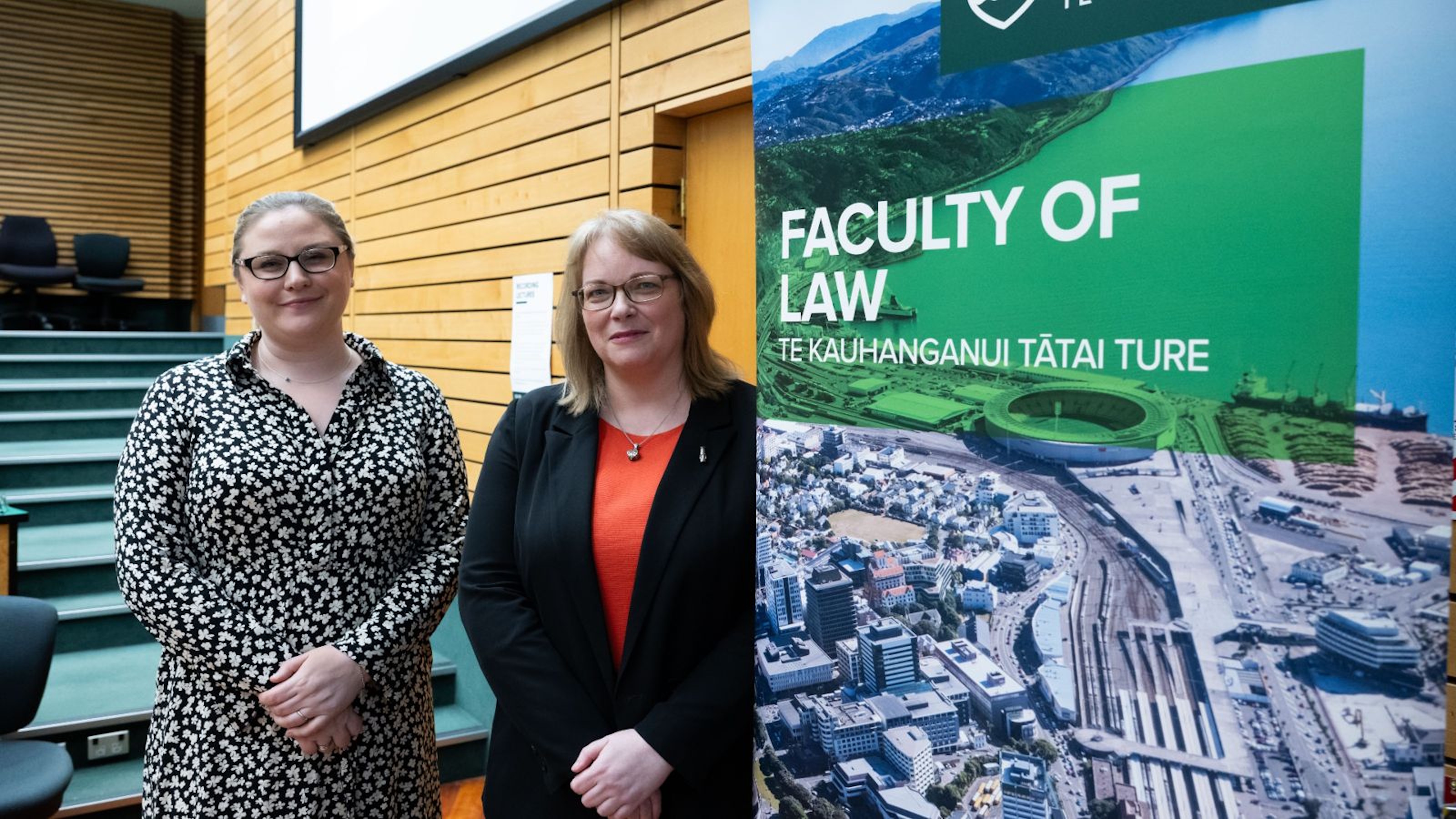 Two women standing in front of a Faculty of Law sign