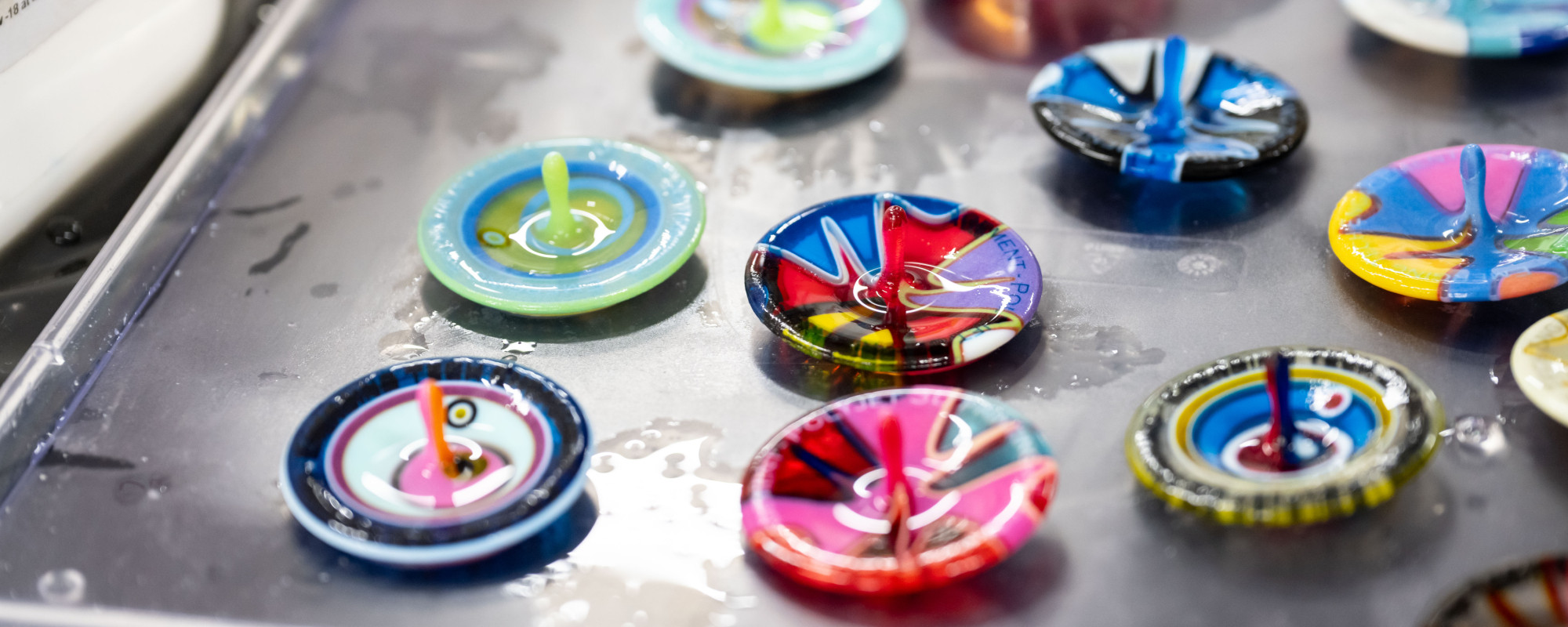 A collection of brightly coloured spinning tops sitting on a bench.