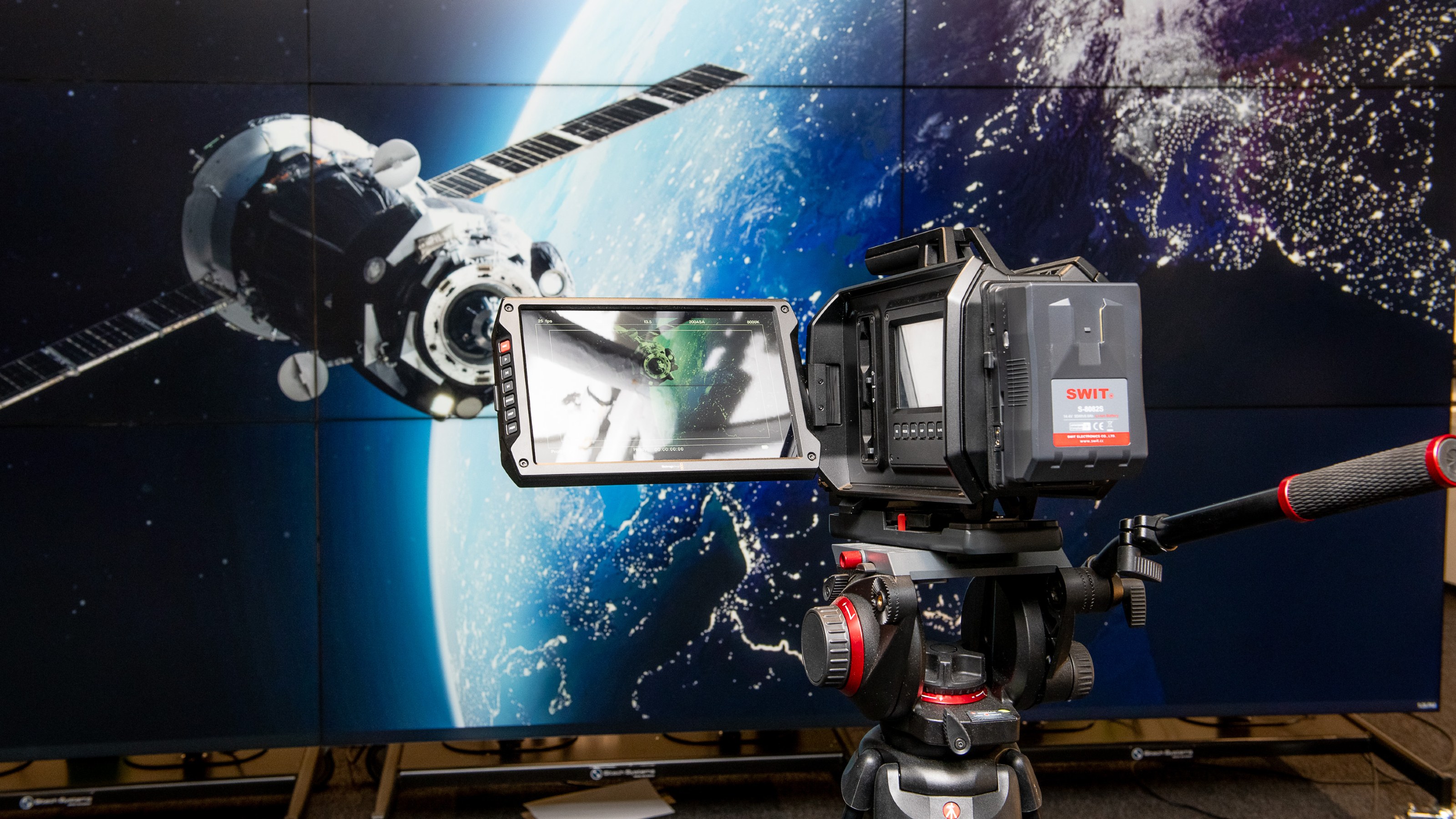 High-end video camera with widescreen image of Earth from space in the background