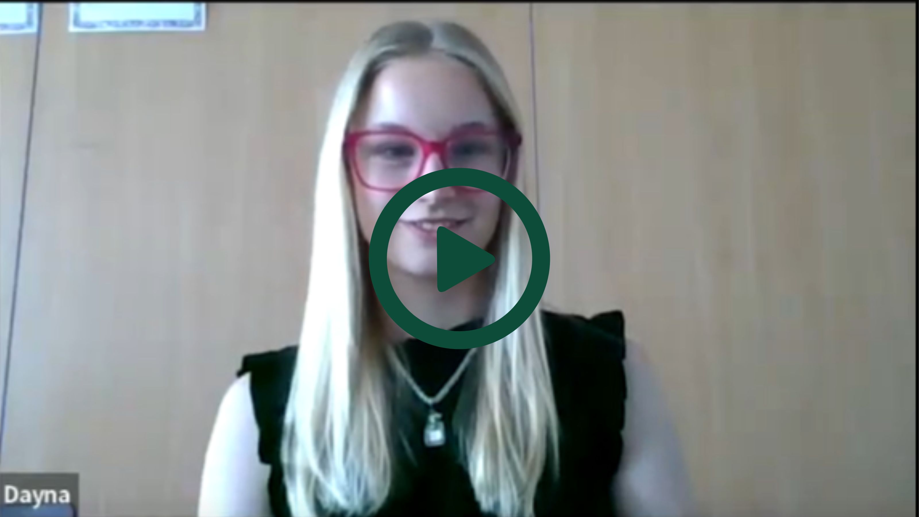 A screenshot of Dayna on a Zoom interview with a play button overlaid