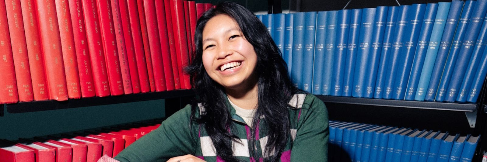 Smiling female Asian student with bound journals in background