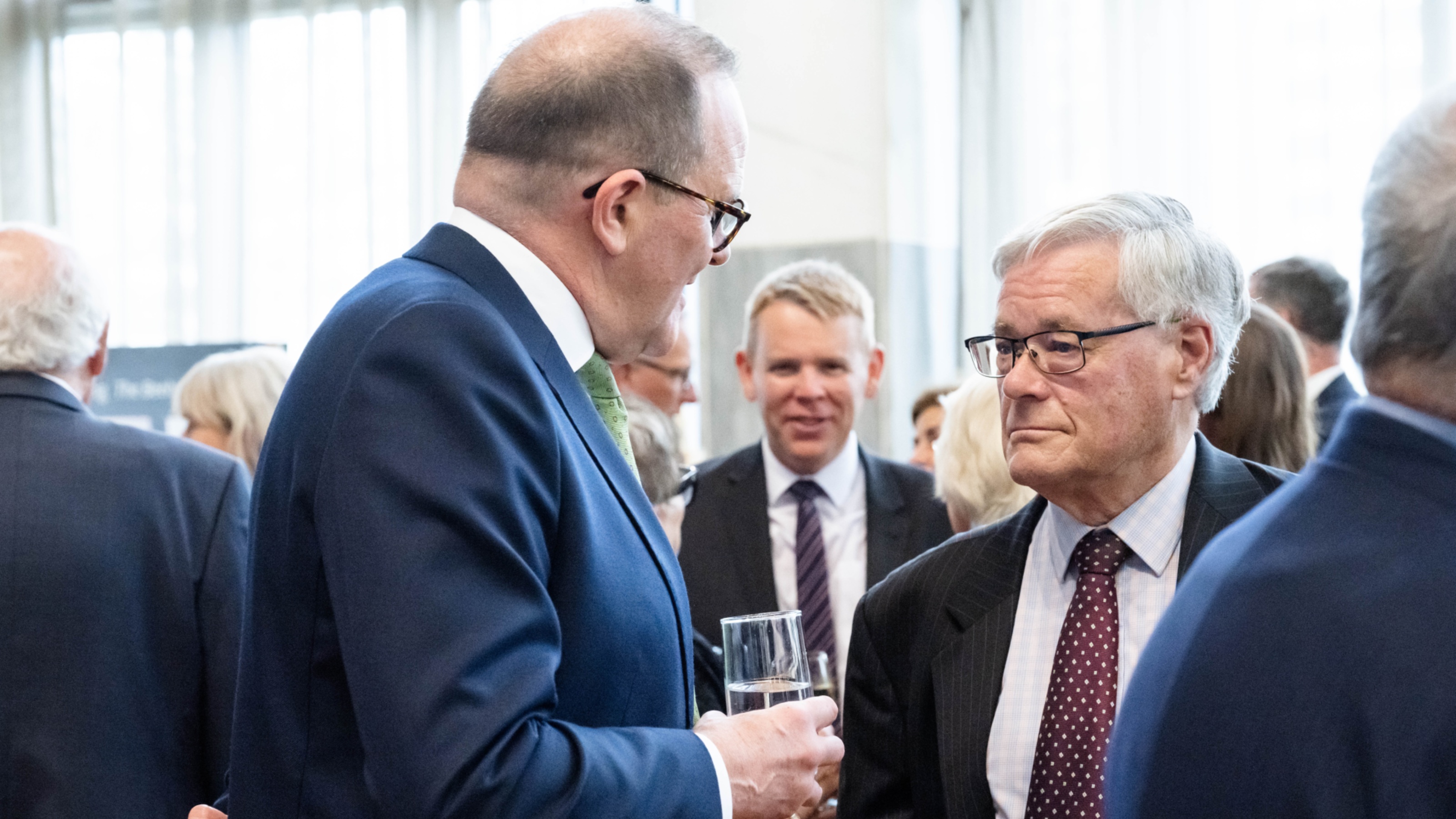 Two men in conversation during an event. One man has his back to the camera.