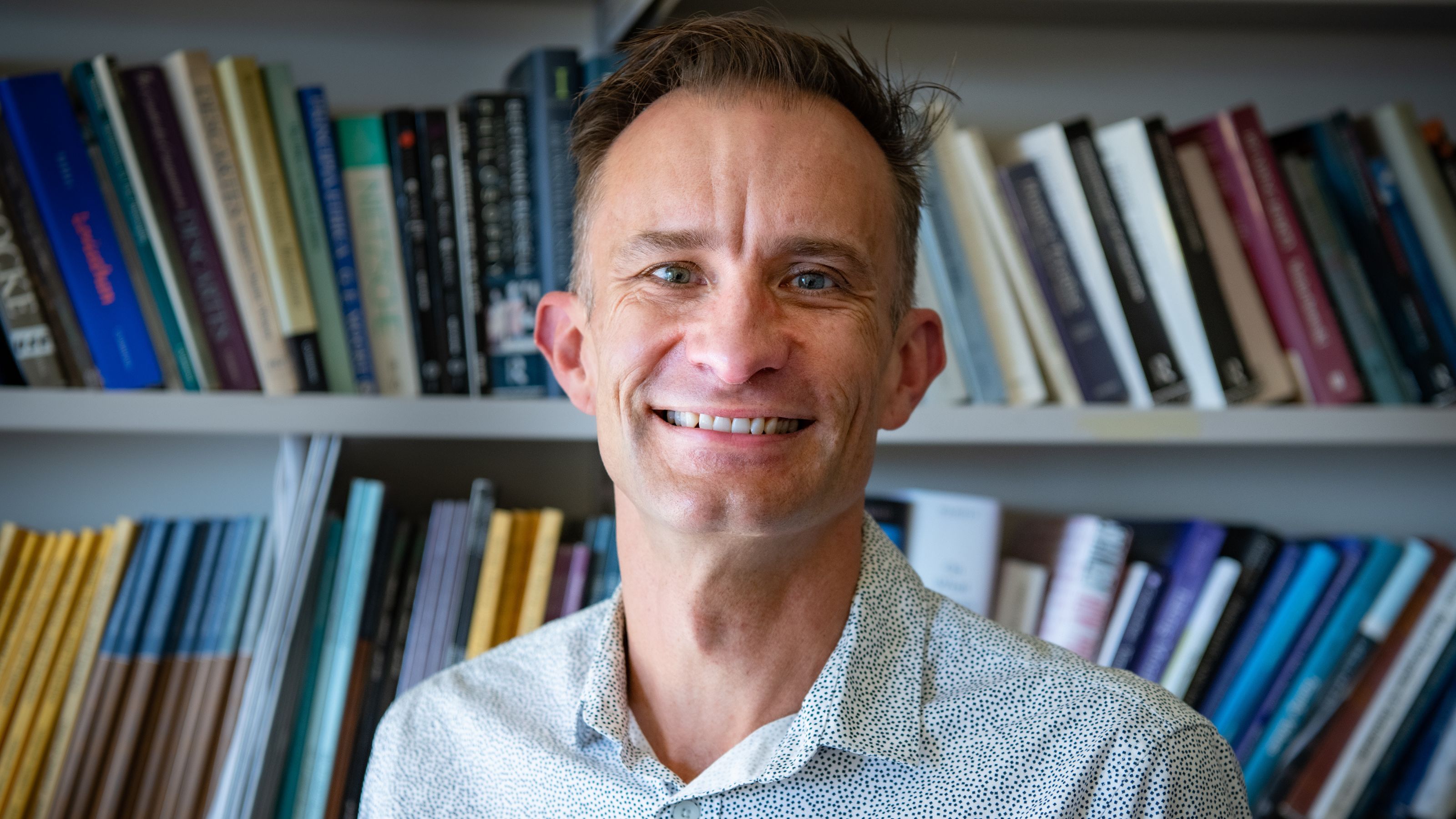 Photo of man smiling with books in background