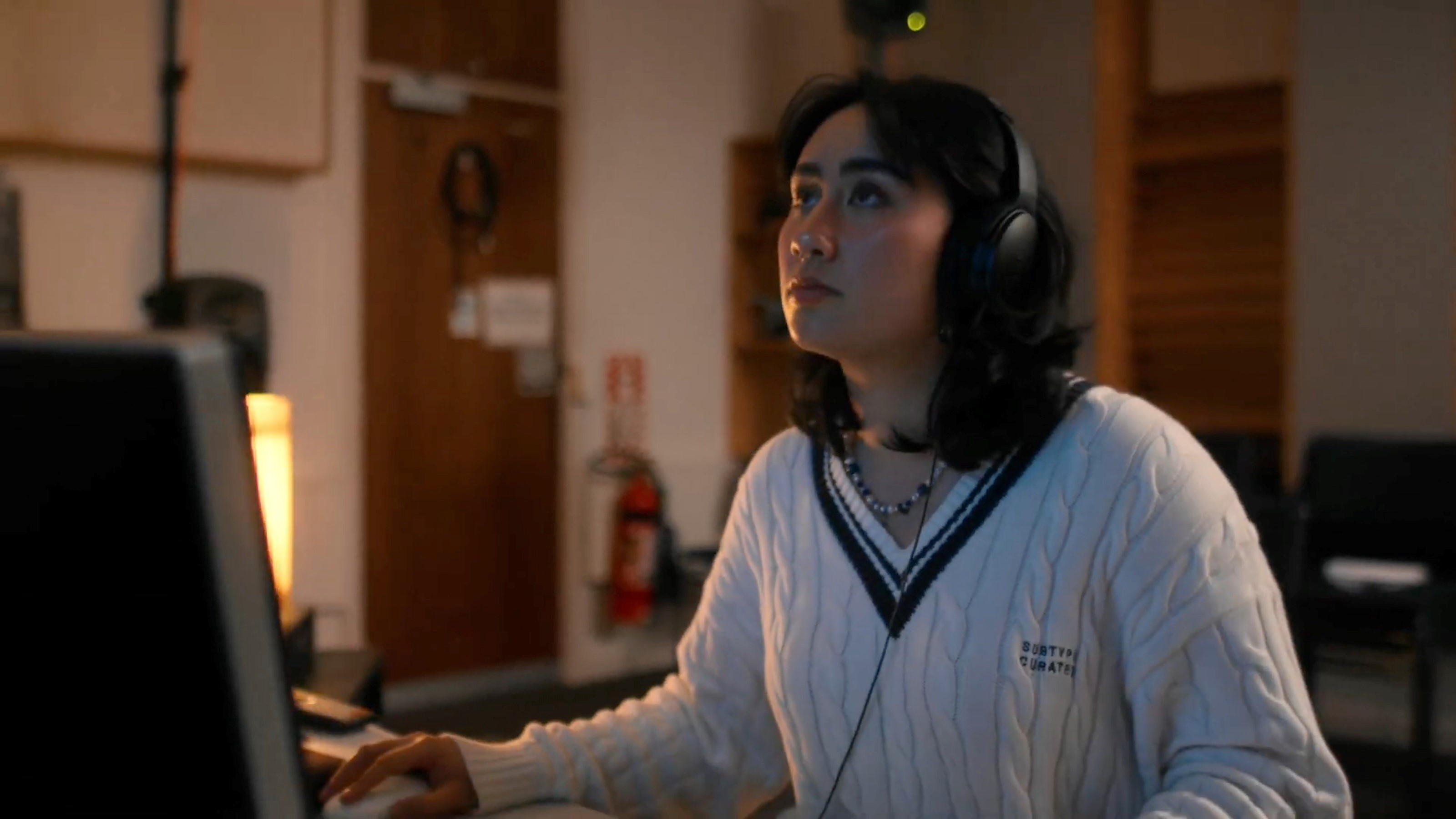 A student with headphones on using the computer in a sound studio.