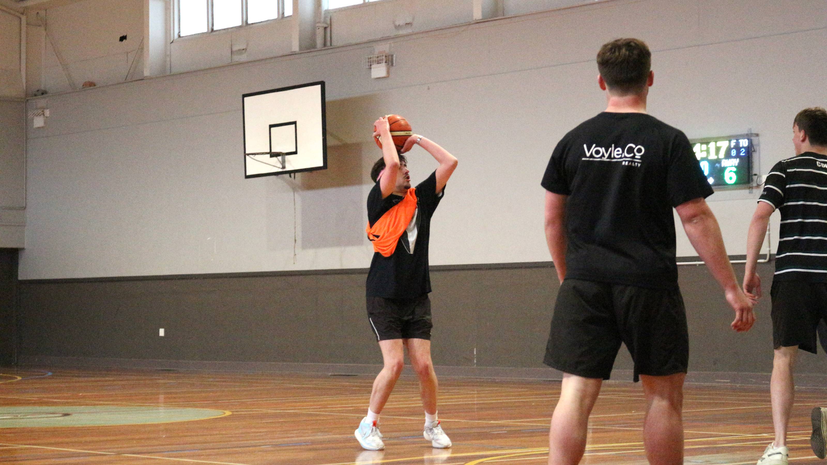 A player with an orange sash attempts a wide open three