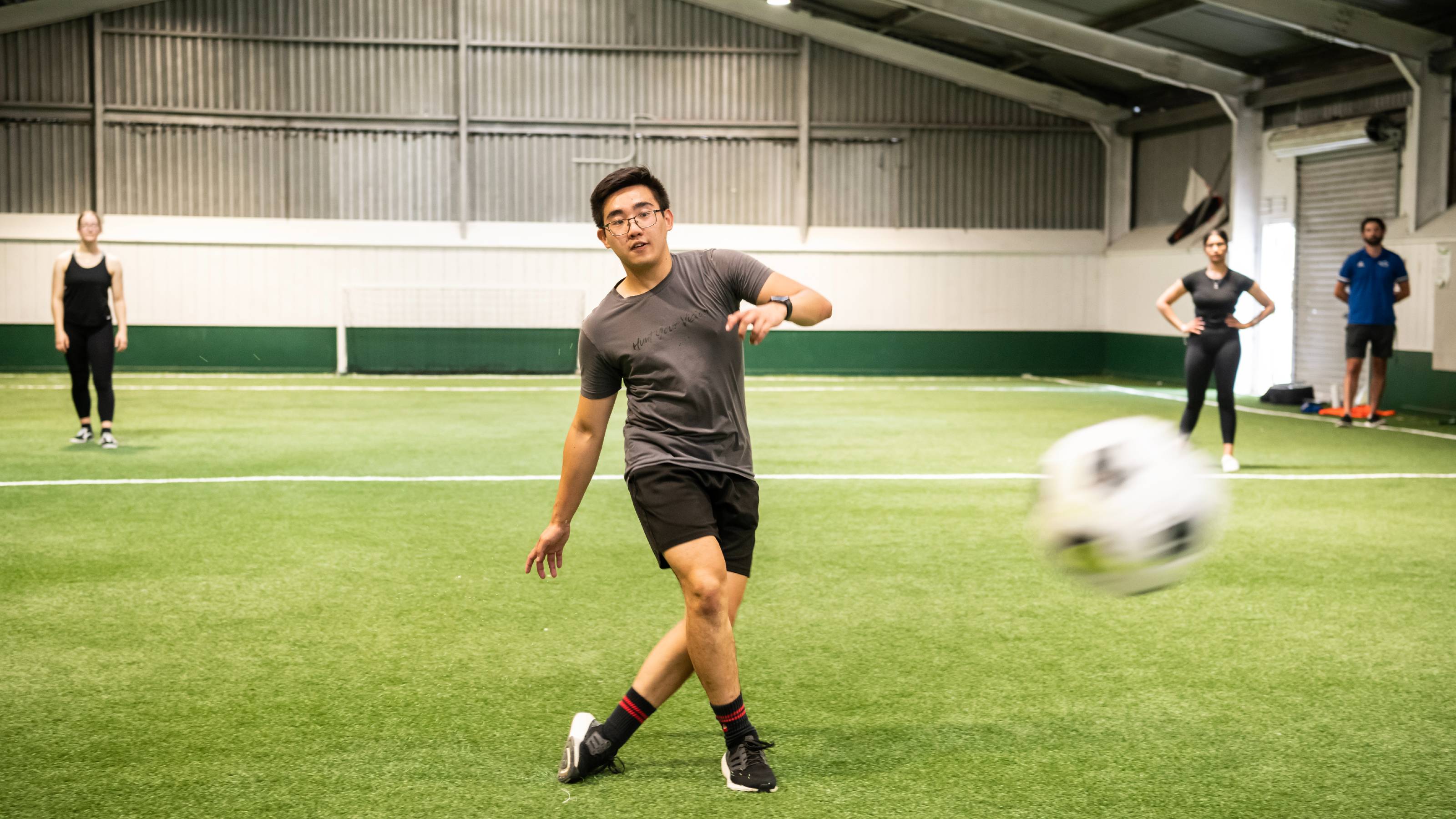 A football player chasing a ball, which appears blurrily in the foreground.