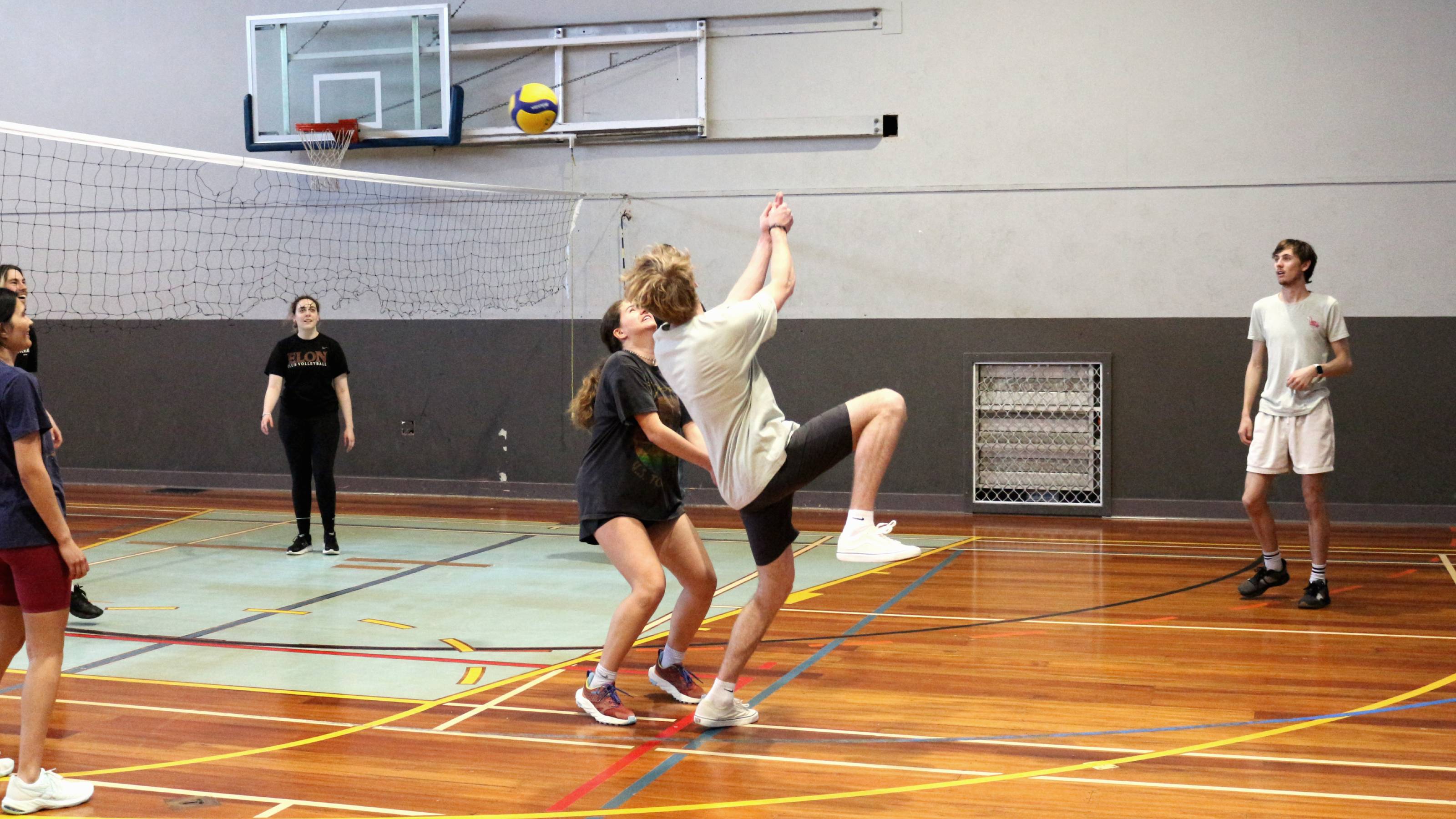 Players dressed in white and black attempting to hit a volleyball over a net