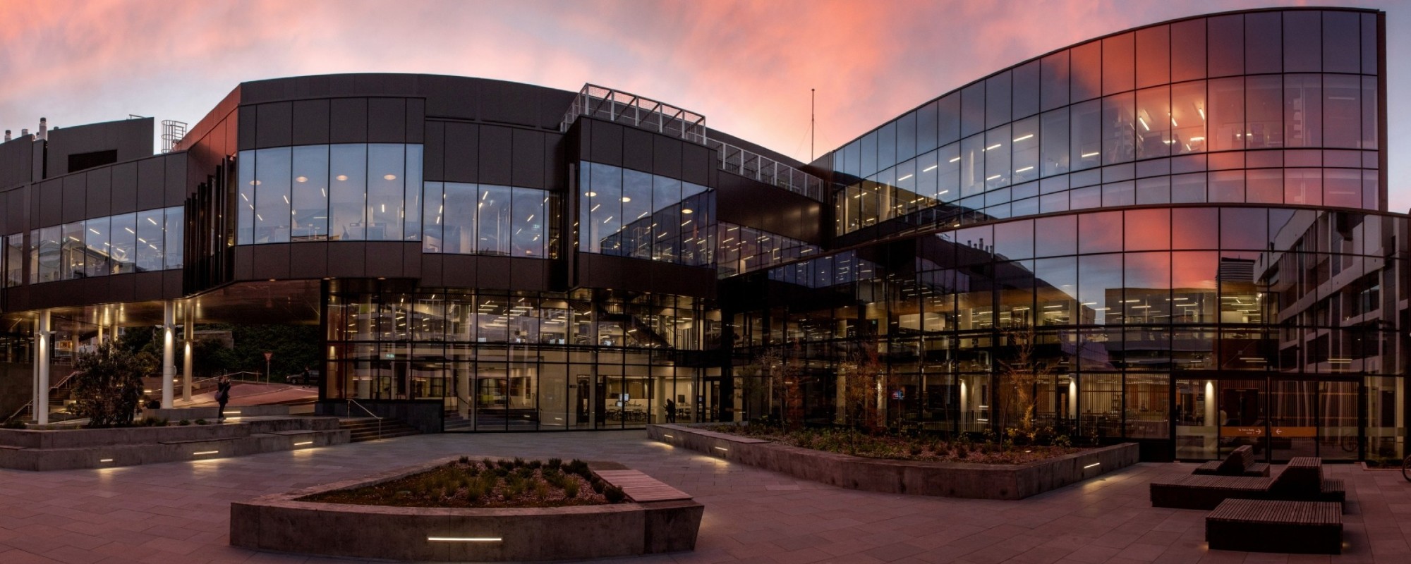 The School of Biology's Te Toki A Rata building at sunset with the sky reflected in the mirrored glass