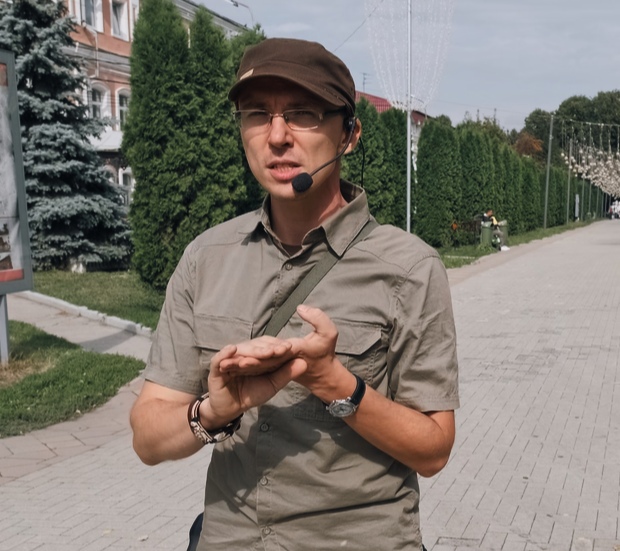 Russian student Valentin Gorbachev, wearing a cap and a headset, standing in a tree-lined street.