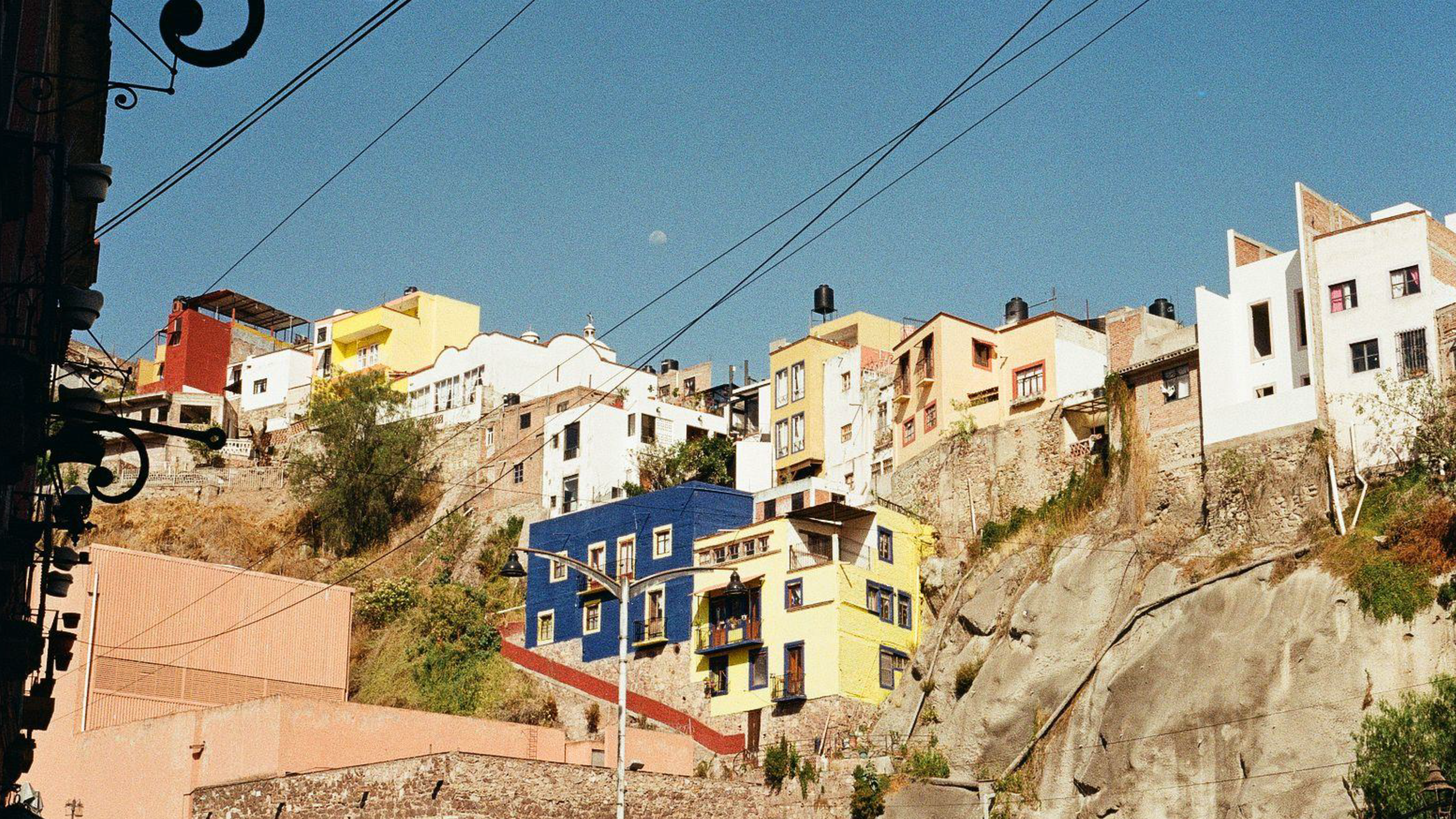 Brightly coloured houses clustered along a steep, rocky hillside in the city of Guanajuato, Mexico.