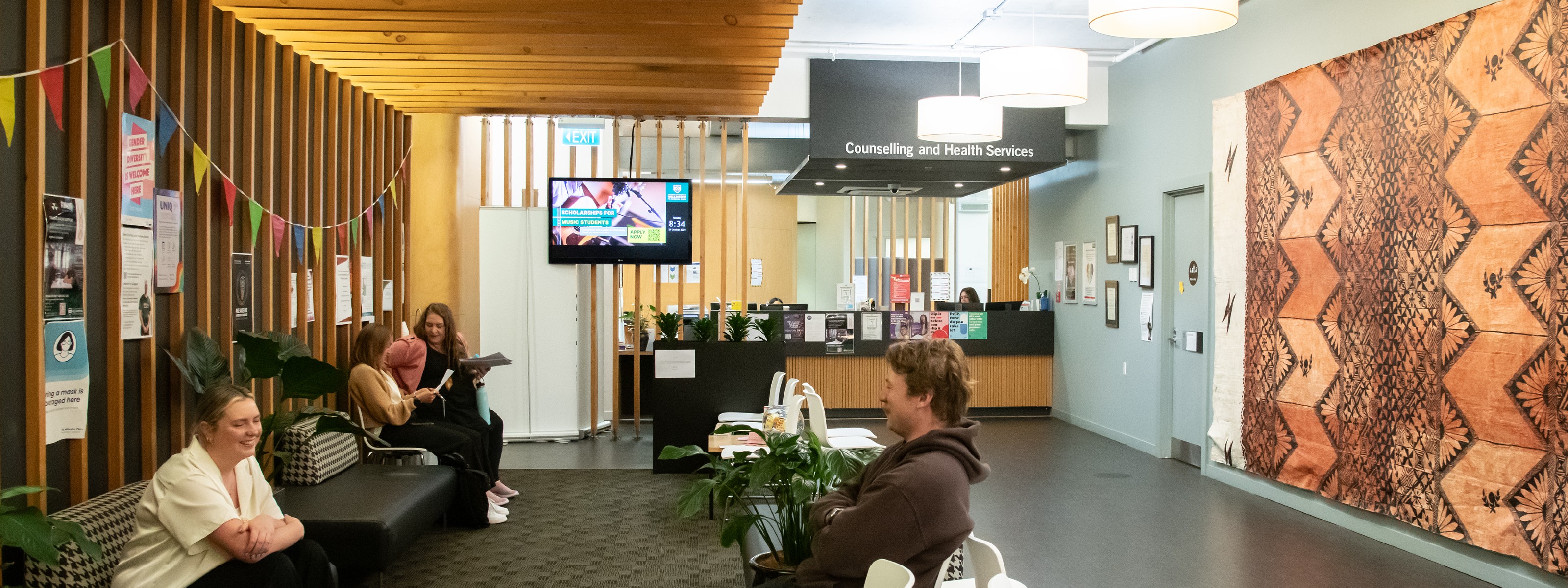 Young female and young male sitting and talking in a waiting room.